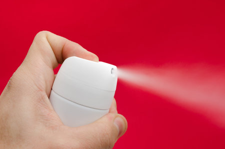 Toxic vapor being sprayed from a white can by a man's hand over an important alerted dangerous red...