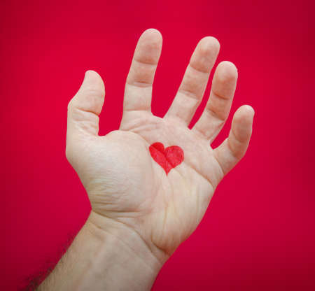Love hurts and creates pain after a relationship is over suggested by a heart on a hand suggesting frustration and pain on a red alerted seriuos backgroundの写真素材