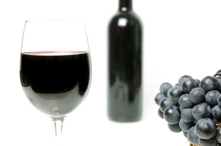 Red wine glass with grapes on white isolated background with bottleの写真素材