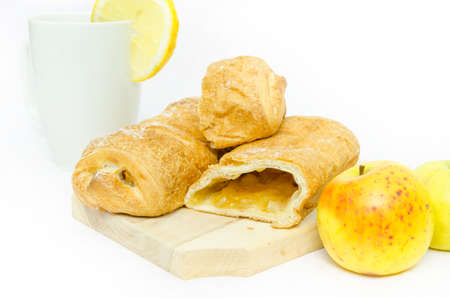 Apple strudle cut with apples on a wood board with a lemon tea on the backgroundの写真素材
