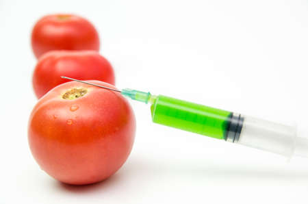 Toxic syringe on some fresh tomatoes indicating dna modificationの写真素材