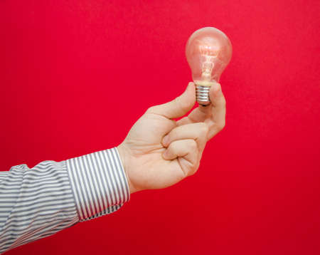 A business man having a bright ideea suggested by holding a lit light bulb with his bare handsの写真素材