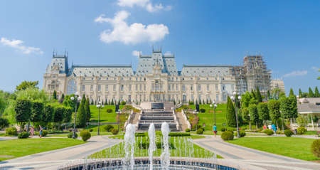 IASI, ROMANIA - 10 AUGUST 2014: Iasi Cultural Palace being restaurated with a beautiful green park and people on a sunny summer dayのeditorial素材