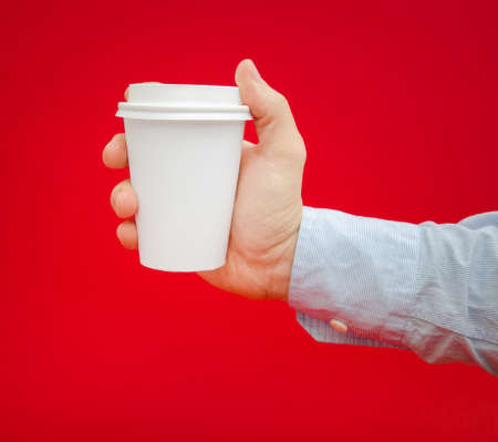 Hot coffee to go being held by a business man over a red alerted dangerous backgroundの写真素材