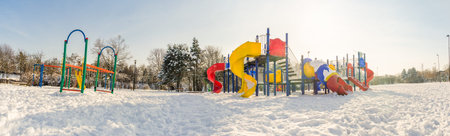 Empty playground in a wide panoramic view during a bright sunny winter day with snowの写真素材