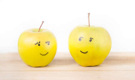 Two yellow green apples in love looking at each other one being a male and the other a female or she apple and he apple on a wood cutting boardの写真素材