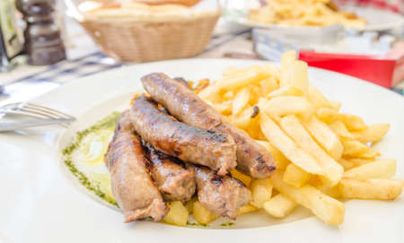 German sausages with french fries on a white plate at a restaurantの写真素材