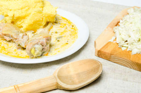 Traditional romanian polenta with lamb chicken stew and cabbage on a wood boardの写真素材