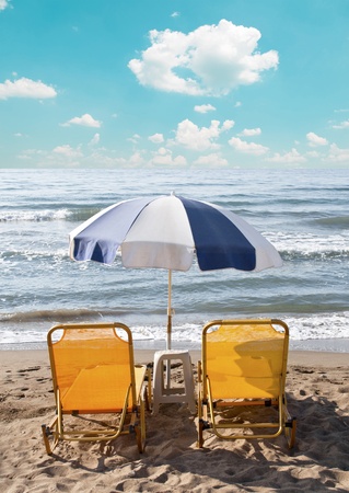 Two loungers under sun umbrella at the beach の写真素材