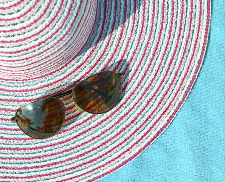 Concept of summer with straw hat and sunglasses on blue towel 