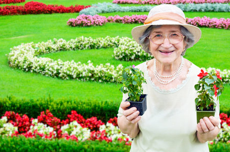 Happy senior woman holding flowers in garden