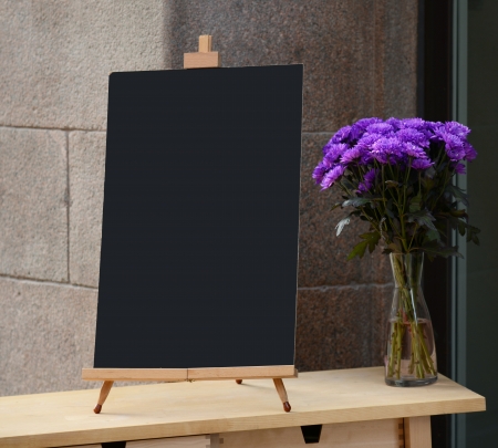 Wooden board for restaurant menu with empty space to add text standing at restaurant entrance with flower potの写真素材