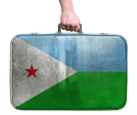 Tourist hand holding vintage leather travel bag with flag of Dijboutiの写真素材