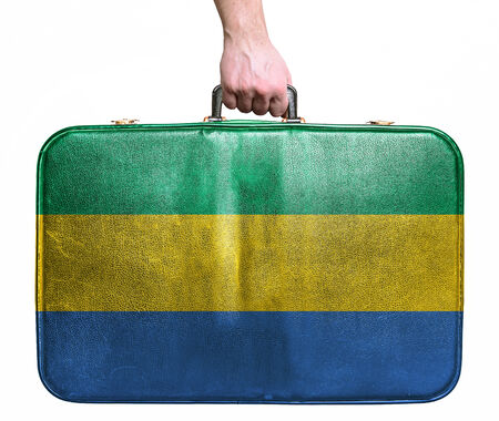 Tourist hand holding vintage leather travel bag with flag of Gabonの写真素材