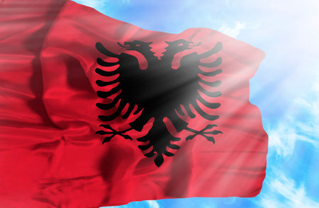 Albania waving flag against blue sky with sunraysの写真素材