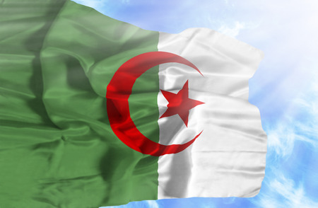 Algeria waving flag against blue sky with sunraysの写真素材