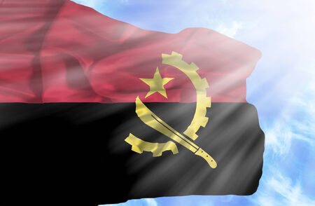 Angola waving flag against blue sky with sunraysの写真素材