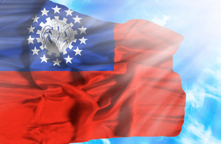 Myanmar waving flag against blue sky with sunraysの写真素材