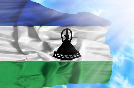 Lesotho waving flag against blue sky with sunrays