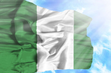 Nigeria waving flag against blue sky with sunraysの写真素材