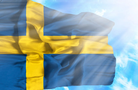 Sweden waving flag against blue sky with sunraysの写真素材