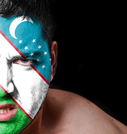Portrait of angry man with painted flag of Uzbekistanの写真素材