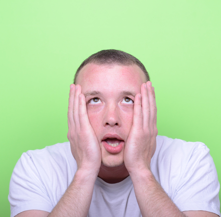 Portrait of sad man looking up against green backgroundの写真素材