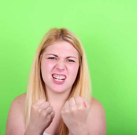 Portrait of angry girl holding fists against green backgroundの写真素材