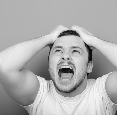 Portrait of angry man screaming and pulling hair - Monocrome or black and white portraitの写真素材