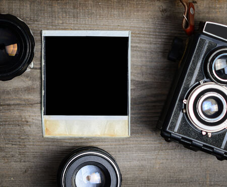 Vintage camera with lenses and blank old photograph on wooden backgroundの写真素材