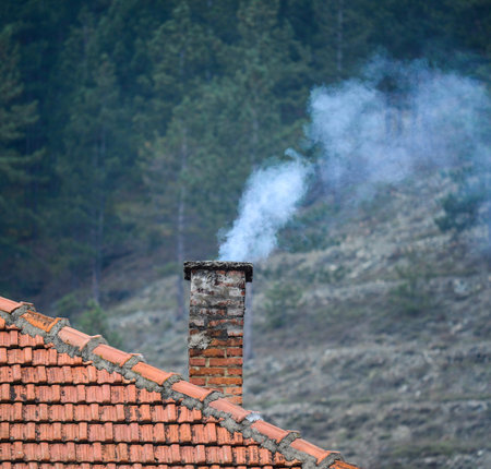 Smoke raising from a chimney in winterの写真素材