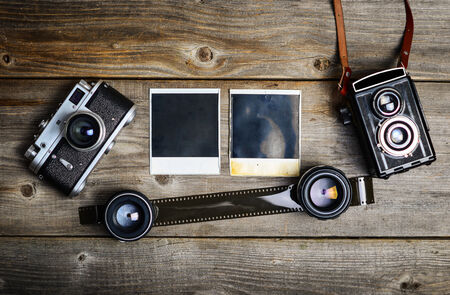 Vintage cameras with lenses and blank old photograph on wooden backgroundの写真素材
