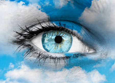 Beautiful blue eye against blue clouds - Spiritual conceptの写真素材