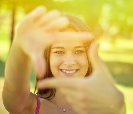 Beautiful girl making frame with hands while outdoorsの写真素材