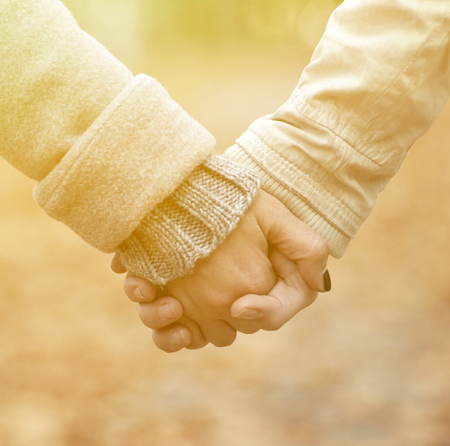 Closeup of couple holding hands while walking in parkの写真素材