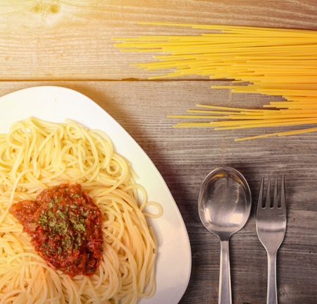 Spaghetti bolognese with  tomato beef sauce and raw pasta on wooden backgroundの写真素材