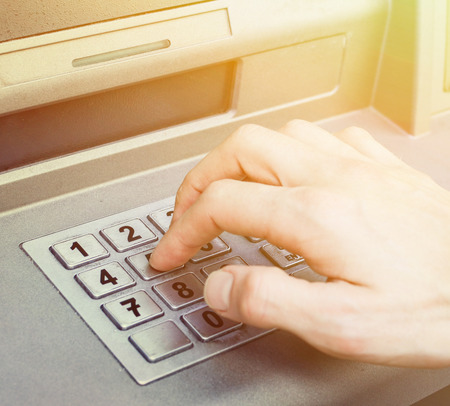 Hand entering PIN numbers on ATM bank machineの写真素材