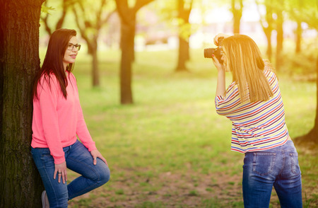 Photographer takes photo of young beautiful brunette woman in parkの写真素材