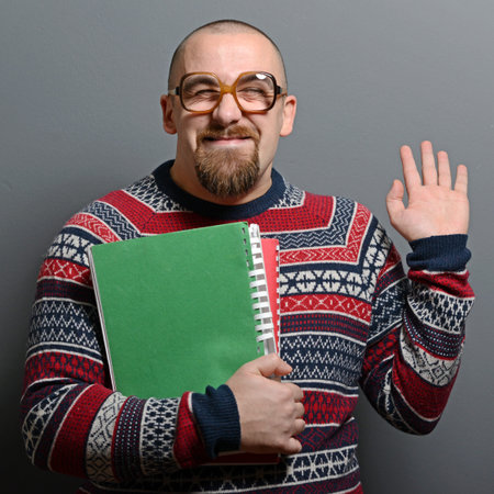 Portrait of a nerd holding book with retro glasses against gray background