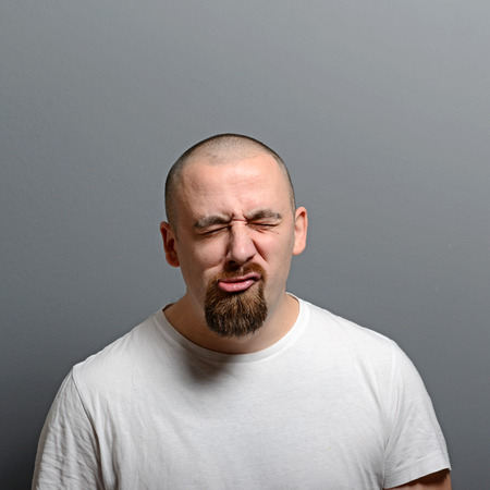 Portrait of a man making funny face against gray backgroundの写真素材