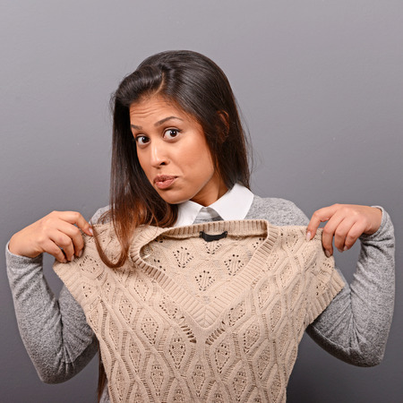 Portrait of a woman choosing clothes against gray backgroundの写真素材
