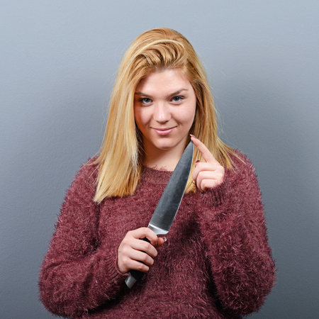 Portrait of killer woman with knife against gray background Portrait of killer woman with knife against gray background