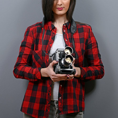 Portrait of hipster girl with retro camera against gray background