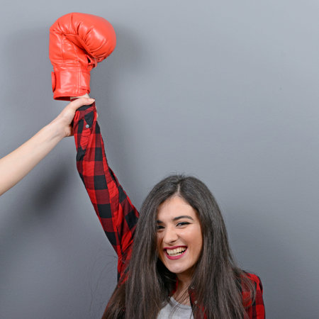 Judge holding hand of woman boxing champion against gray background.