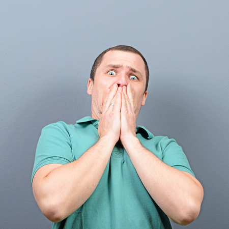 Portrait of shocked man against gray backgroundの写真素材