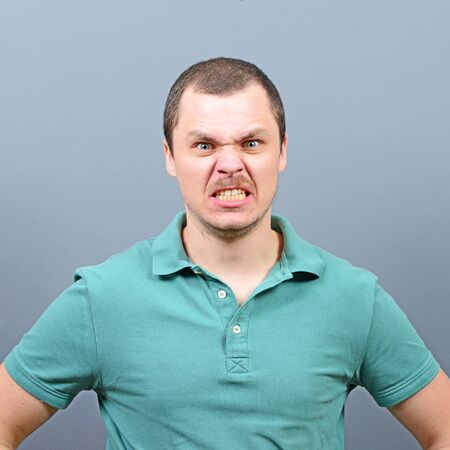 Portrait of a mad looking man against gray backgroundの写真素材