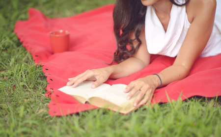 Young beautiful woman reading book outdoors in park on a sunny dayの写真素材