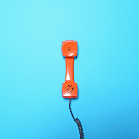 Retro orange telephone tube on blue background - Flat layの写真素材