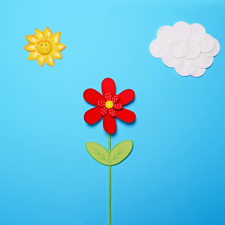 Fairy tail scene made of various objects on blue paper - Childrens story background - Cotton clouds and sun with red wooden flower against blue paper - Flat layの写真素材