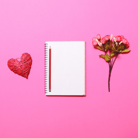 Writers dream table - Perfect day start with notebook and flowers and red heart on pink background -...